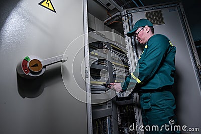 Electrician engineer is testing electrical equipment at a large plant. Editorial Stock Photo