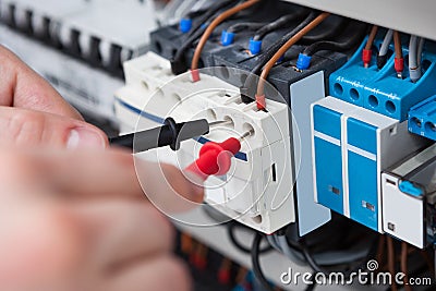 Electrician examining fusebox with multimeter probe Stock Photo