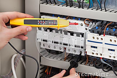 Electrician examining fusebox with voltage tester Stock Photo