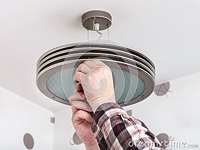 Electrician fixes round ceiling light Stock Photo