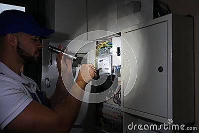 Electrician with flashlight fixing electric panel Stock Photo