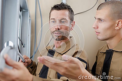 Electrician guiding apprentice in connecting wires Stock Photo