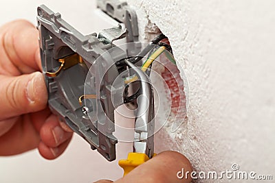 Electrician hands installing wires into electrical outlet Stock Photo