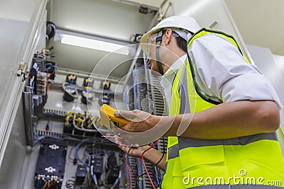 Electrician installing electric cable wires and fuse switch box. Multimeter in hands of electricians detail.Electrician repairing Stock Photo