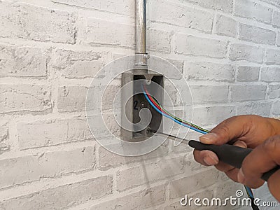 Electrician installing F.S. BOX for electrical system work on gray brick wall.Technician installation electrical system work. Stock Photo