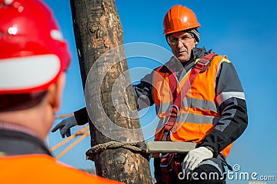 Electrician on a pole against the blue sky Editorial Stock Photo