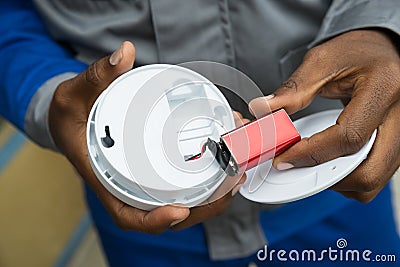 Electrician Removing Battery From Smoke Detector Stock Photo