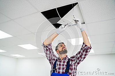 Electrician On Stepladder Installs Lighting To The Ceiling Stock Photo