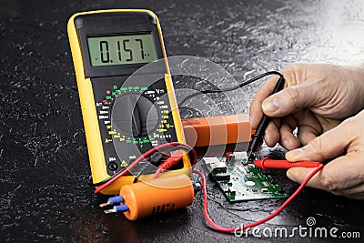 An electrician takes readings from a microcircuit using a multimeter. Measuring instruments. Copy space. Voltage Stock Photo