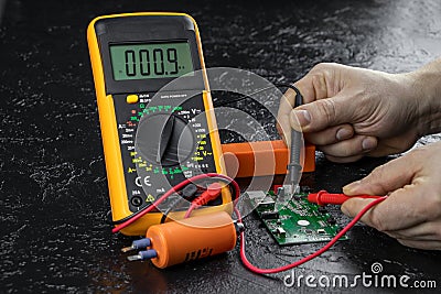 An electrician takes readings from a microcircuit using a multimeter. Measuring instruments. Voltage measuring tool Stock Photo