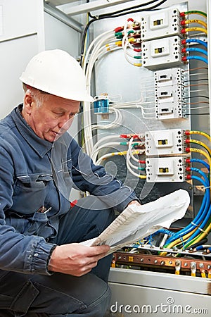 Electrician at wiring with working drawings Stock Photo