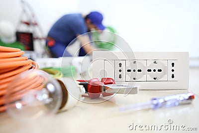 Electrician work with electrical equipment in the foreground bulb, tools and socket, electric circuits, electrical wiring Stock Photo