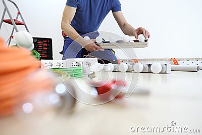 Electrician at work installing lamp, with bulb in hand, install electric circuits, electrical wiring. Stock Photo