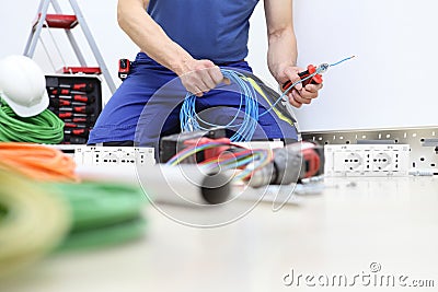 Electrician at work with nippers in hand cut the electric cable install electric circuits, electrical wiring Stock Photo