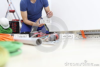 Electrician at work with screwdriver in hand connects the cables to the socket, electric circuits, electrical wiring Stock Photo