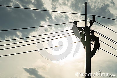 Electrician worker climbing electric power pole to repair the damaged power cable line problems after the storm. Power line Stock Photo