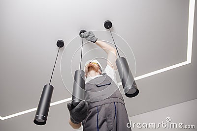 Electrician worker installation electric lamps light inside apartment. Construction decoration concept Stock Photo