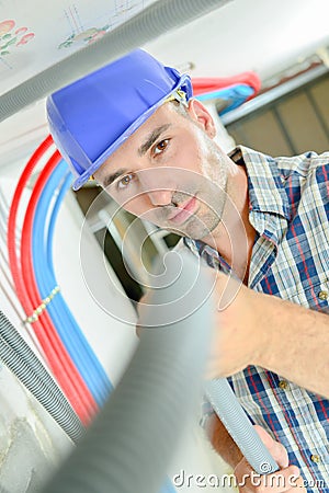 Electrician working through open ceiling hatch Stock Photo