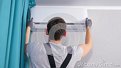 Electrician opens air conditioner lid and takes out screws Stock Photo