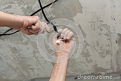 Electricians cleans the contacts with pliers. Installing the ceiling light Stock Photo