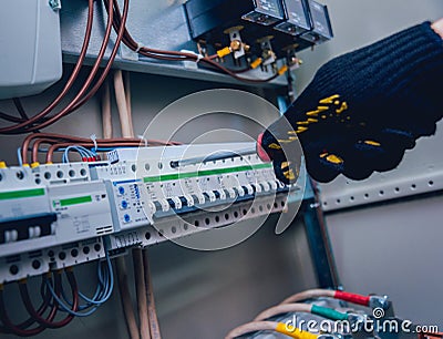 Electricians hands testing switches in electric box. Electrical panel with fuses Stock Photo