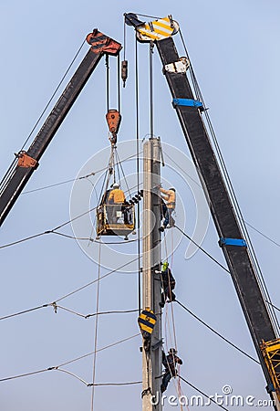 Electricians repairing wire on electricity power pole with hydraulic platform. Stock Photo