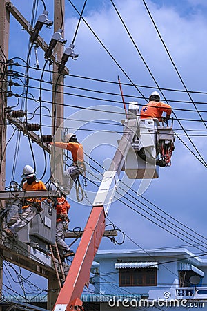 Electricians team with crane truck are working to install electrical systems on power poles against blue sky Editorial Stock Photo