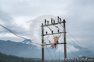 Electricians working high on electricity pole in Vietnam Stock Photo