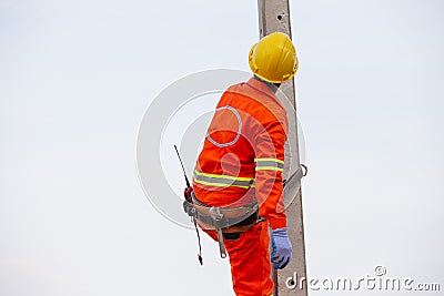 Uniformed electricians working on high-voltage electricity poles with safety equipment Stock Photo