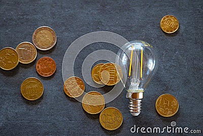 electricity prices in Europe.Saving electricity concept.Electricity cost.Light bulb and euro coins on black chalk board Stock Photo