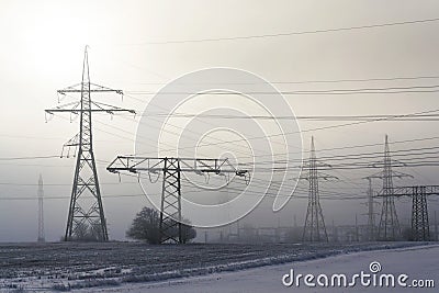 Electricity pylons from distribution power station in foggy winter freeze Stock Photo