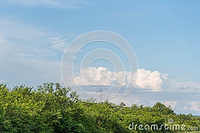 Electricity transmission tower and in the background cumolunimbus clouds on the blue horizon Stock Photo