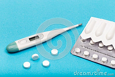 Electrick thermometer , plastic packs of suppositories and tablets on blue background Stock Photo