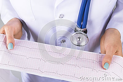 Electrocardiogram, ecg in hand of a female doctor. Medical health care. Clinic cardiology heart rhythm and pulse test closeup. Stock Photo
