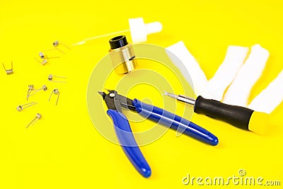 Electronic cigarette details, Vata, coils, drip, spring, nippers on a yellow background. flat lay vape. Stock Photo