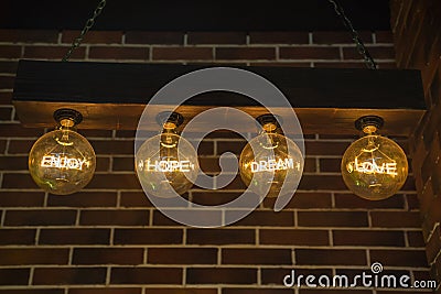 Electronic lamps suspended from the ceiling with the words enjoy hope dream love on a dark background. Interior style Stock Photo