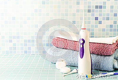 Electronic tooth irrigator, toothbrushes and a pile of towels front view copy space Stock Photo