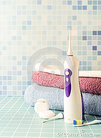 Electronic tooth irrigator, toothbrushes and a pile of towels front view copy space Stock Photo