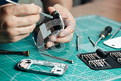 Electronics repair service. Technician disassembling smartphone for inspecting Stock Photo