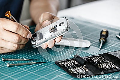 Electronics repair service. Technician disassembling smartphone for inspecting Stock Photo