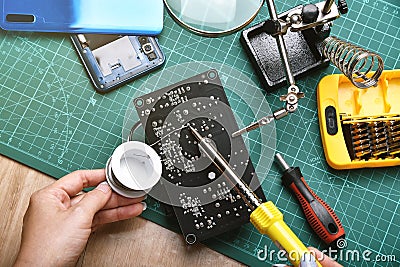 Electronics repair service, Technician fixing electronic circuit board with soldering iron and tin Stock Photo