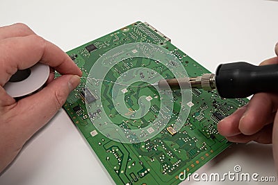 Electronics repair. Technician soldering component on circuit board. Stock Photo