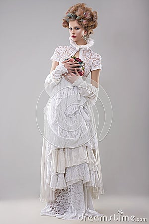 Elegance. Gorgeous Fashion Model in Long Gown and Bouquet of Flowers Stock Photo