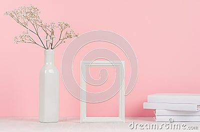 Elegance home interior of small dry flowers in vase, white books and blank wood photo frame on light pink background. Stock Photo