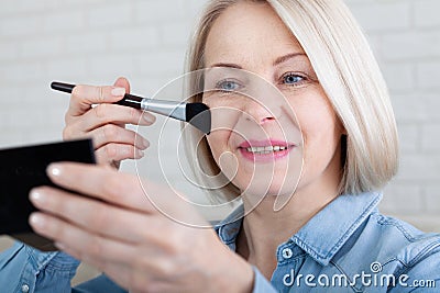 Elegance in Reflection. Captivating shot of a woman skillfully applying makeup before a vanity mirror, creating a timeless beauty Stock Photo
