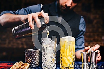 Vintage bartender pouring fresh orange vodka cocktail over ice in crystal glassware Stock Photo