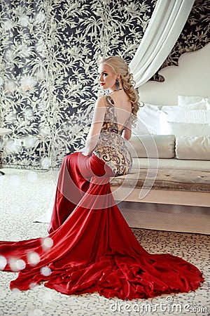 Elegant blond woman model wearing in luxurious red gown with lon Stock Photo