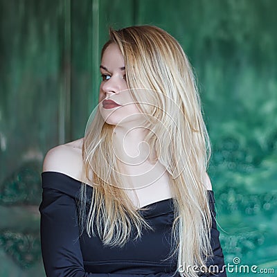 Elegant blonde in a black dress near grunge wall Stock Photo