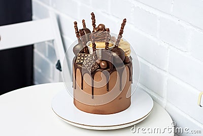 Elegant chocolate birthday cake with melted dark chocolate, cupcake, cake pops, cookies and candy on white background. Stock Photo