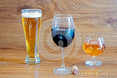 Composition of alcoholic drinks with glass of whiskey, glass of clear beer and glass of red wine on stage of oak tables with a Stock Photo
